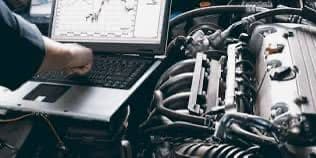 Mechanic using diagnostic software on a laptop connected to a car engine at Handy Speedy